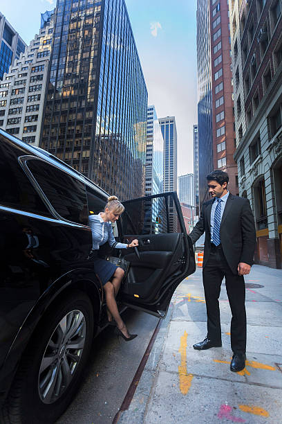 A man and woman stand beside a sleek black car, showcasing elegance and sophistication in limousine service.