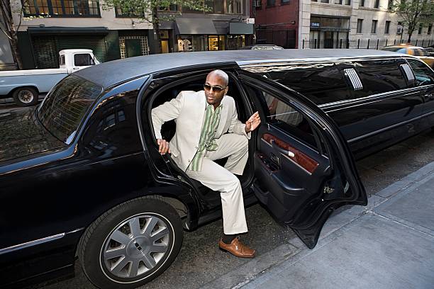 A man in a suit elegantly exits a limousine, showcasing the luxury of premium limousine service.